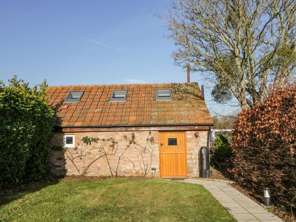 uma pequena casa com uma porta laranja num quintal em The Forge em Taunton