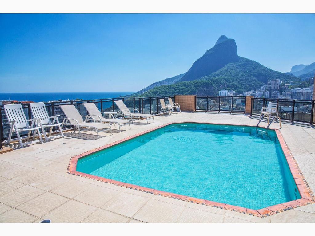 a swimming pool on a balcony with chairs and the ocean at Top Apart Leblon - com piscina na cobertura, sala de ginastica e garagem in Rio de Janeiro