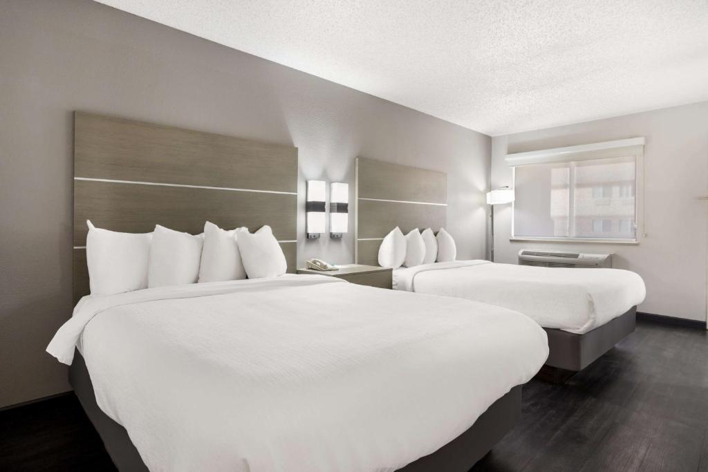 two beds in a hotel room with white sheets at SureStay Hotel by Best Western Grants in Grants