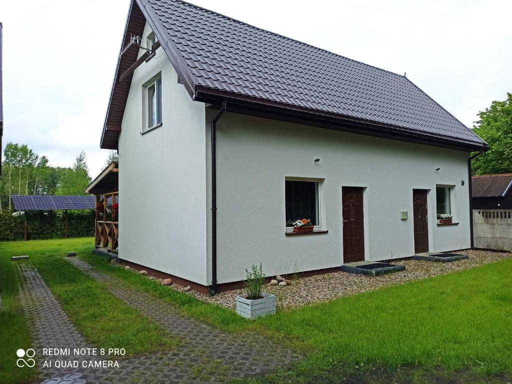 ein weißes Haus mit schwarzem Dach in der Unterkunft Apartameny Wiktoria i Nikola w Karwiku in Pisz