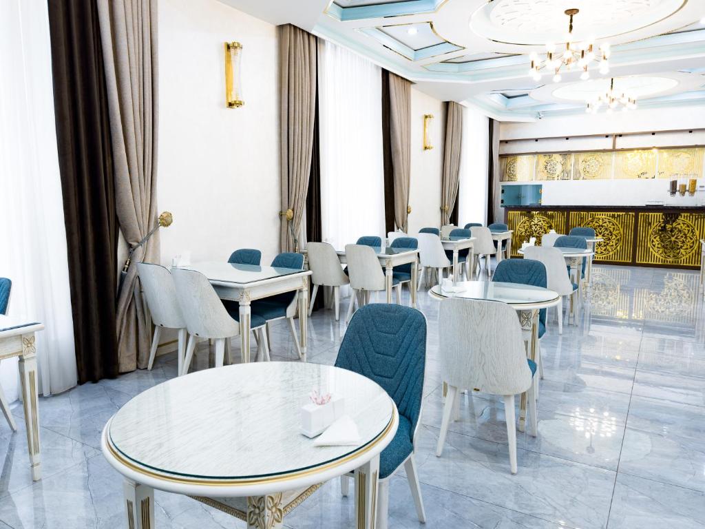 a restaurant with tables and chairs and a chandelier at Reikartz Amirun Tashkent in Tashkent