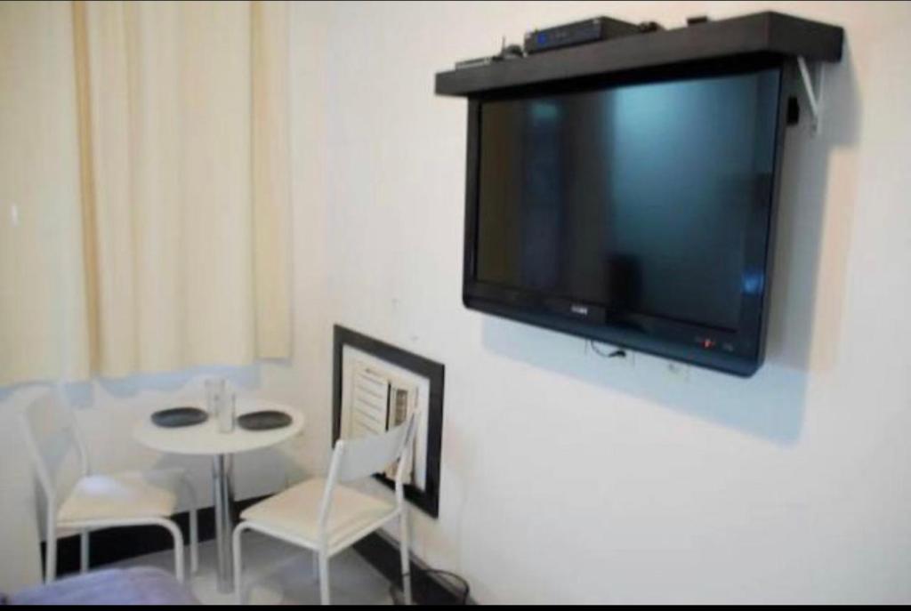 TV colgada en una pared con mesa y sillas en Copa Studio near the sea, en Río de Janeiro