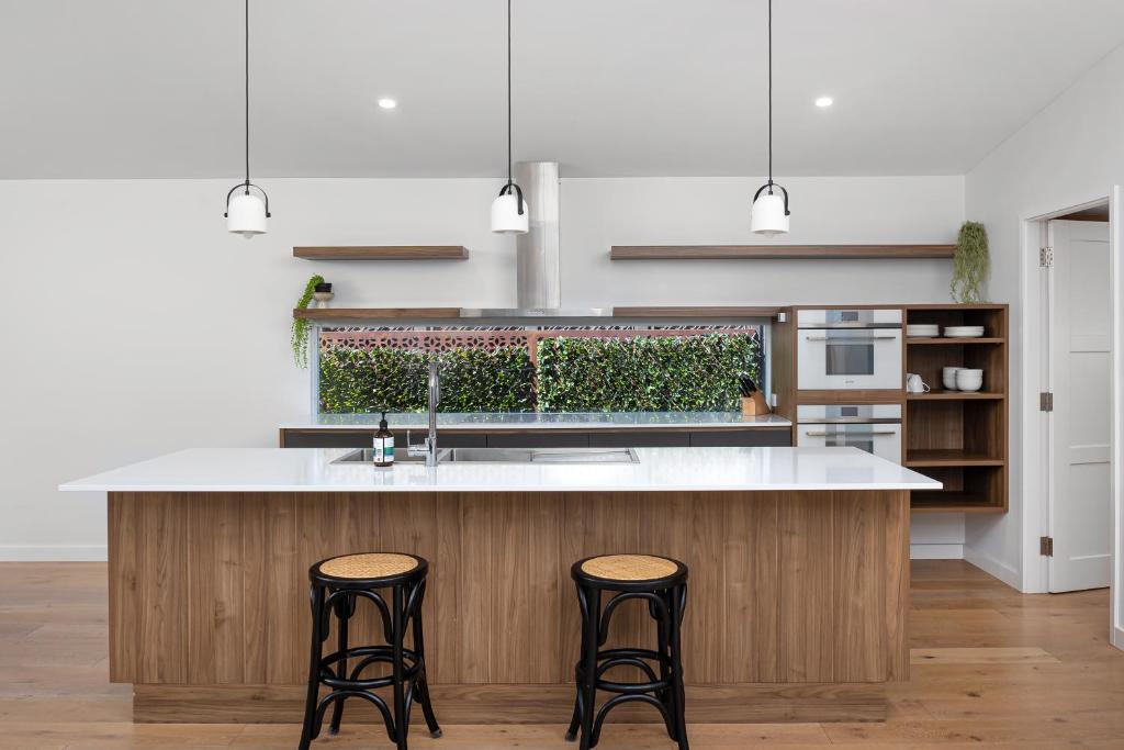 a kitchen with a large island with two bar stools at New luxury home, walking distance to CBD in Wagga Wagga