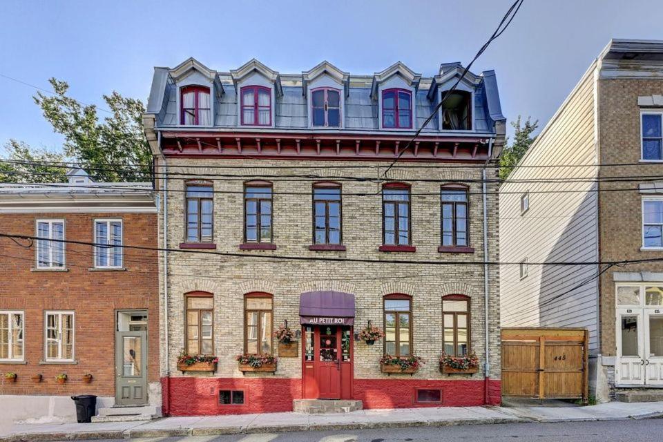 un antiguo edificio de ladrillo con una puerta roja en B&B Au Petit Roi, en Quebec