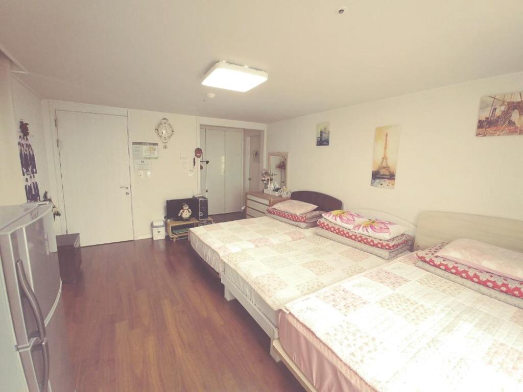 2 łóżka w pokoju z drewnianą podłogą w obiekcie Sky Cozy House w Seulu