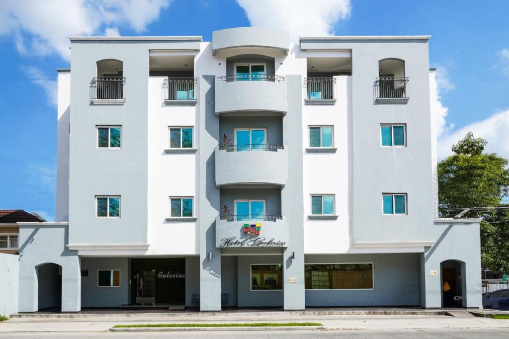 a white building with blue windows at Hotel Galerias HN in San Pedro Sula