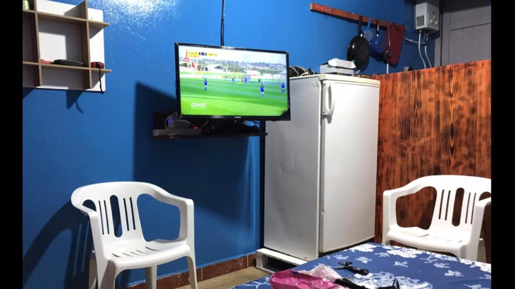 een woonkamer met twee witte stoelen en een televisie bij Studio tan tan in Tan-Tan Plage