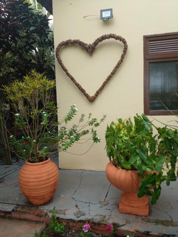 a heart hanging on a wall next to two vases at Pousada Sol das Amendoeiras in Saquarema