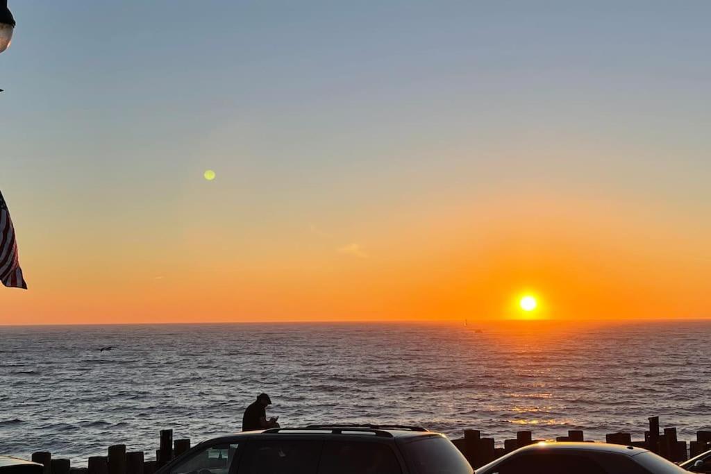 un hombre sentado en la parte superior de un coche viendo la puesta de sol en SouthBAY Beaches Beauty&Cozy Apt, en Gardena