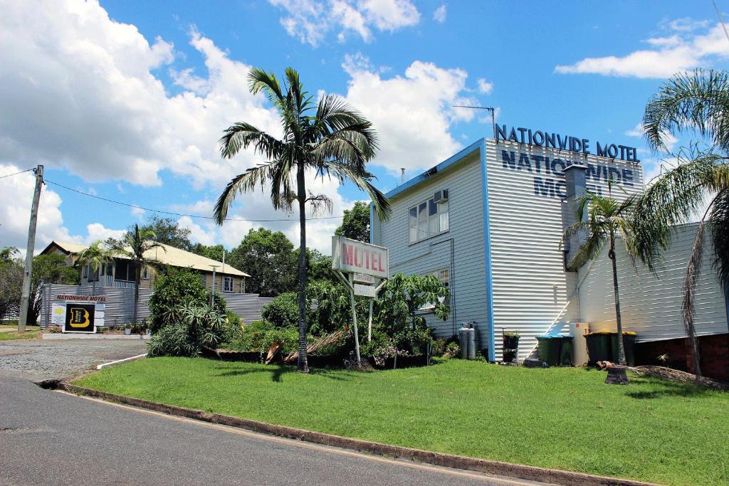 un bâtiment avec un palmier à côté d'une rue dans l'établissement Nationwide Motel, à Gympie