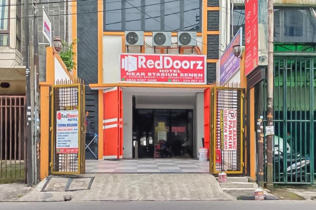 una entrada a un edificio con una puerta roja en RedDoorz near Stasiun Senen, en Yakarta