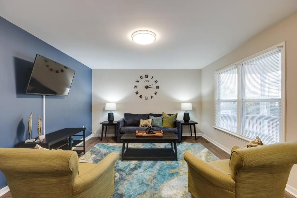 a living room with a couch and a clock on the wall at The Neighborhood House in Richmond in Richmond