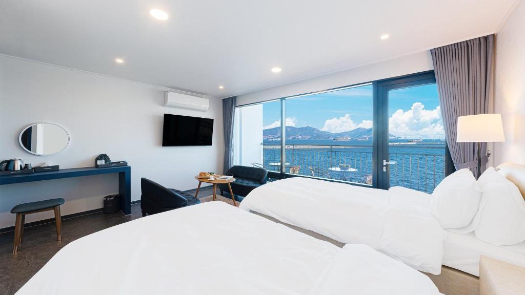 a hotel room with two beds and a large window at Hotel C Resort in Yeosu