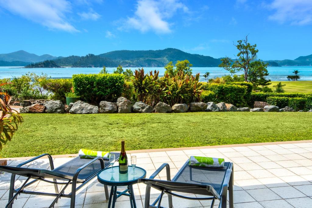 a table and two chairs and a bottle of wine at Frangipani Beachfront Lodge F5 on Hamilton Island by HamoRent in Hamilton Island