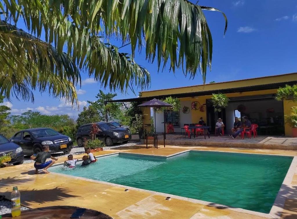 eine Familie spielt in einem Pool vor einem Haus in der Unterkunft LA POSADA DORADA PARCELAS NAPOLES in Doradal