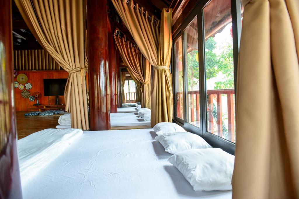 a large bed with pillows in a room with windows at Đào Hoa Glamping in Hanoi