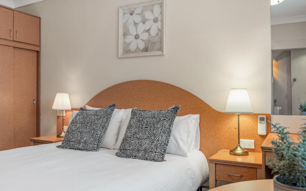 a bedroom with a white bed with pillows at Blue Mountains Heritage Motel in Katoomba