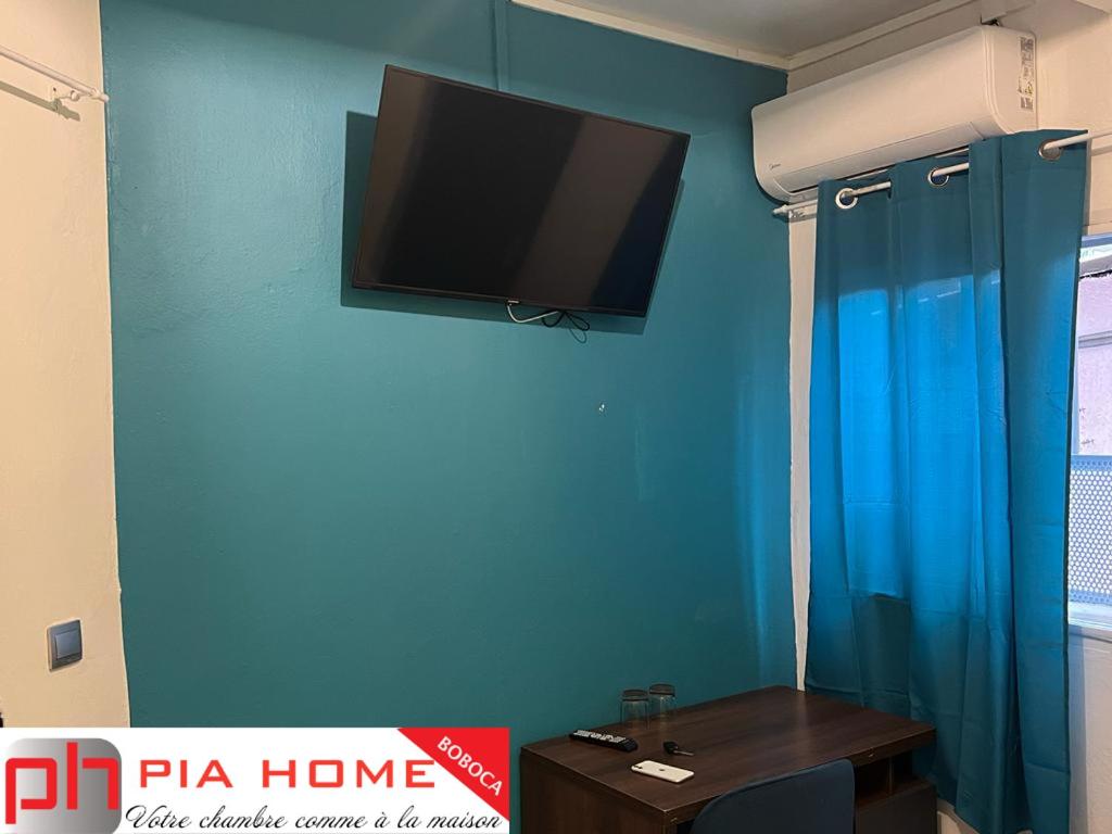 a room with a flat screen tv on a blue wall at PIA HOME La Pompe in Mamoudzou