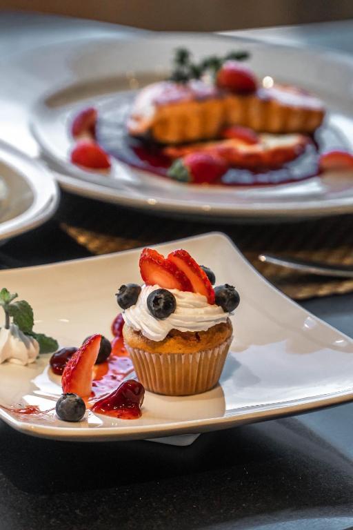 A fruit-topped cupcake presented with berry sauce on a dark tabletop.