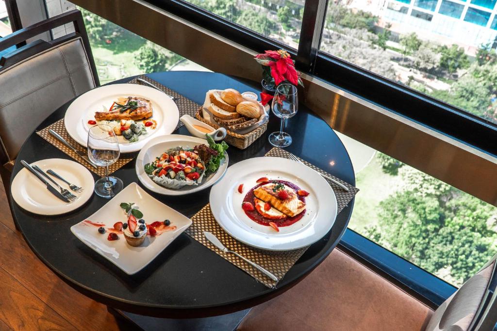A set table for two beside large windows, overlooking greenery and nearby buildings.
