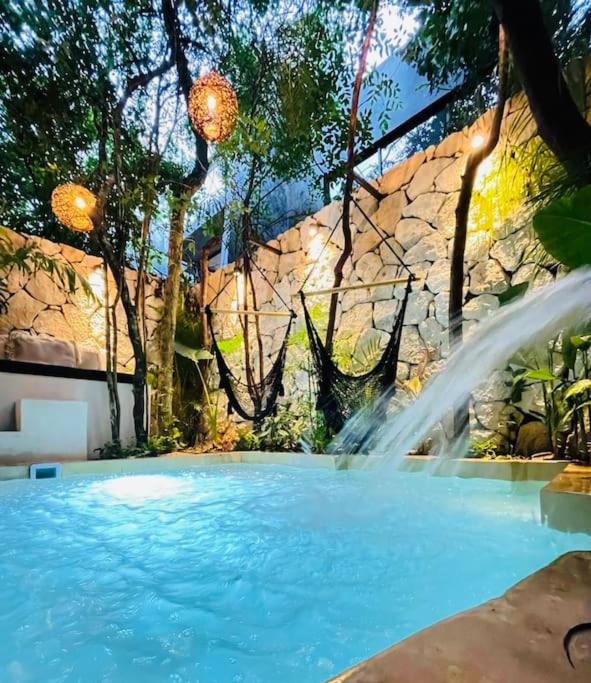 a swimming pool with a water fountain at Luz de Luna Tulum Villa in Tulum