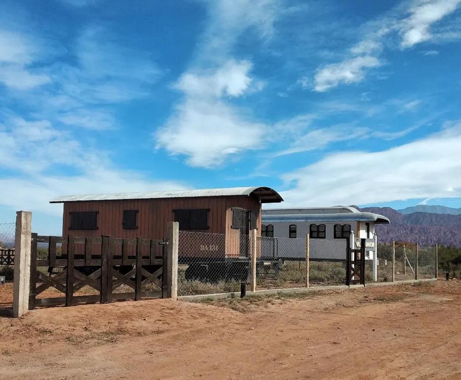 a building in the middle of a field with a fence at Tren Del Desierto in Villa Unión