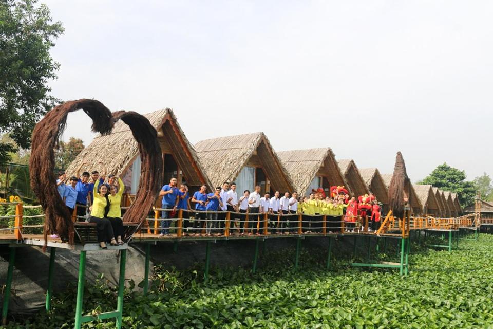 een groep mensen die op een brug voor hutten staan bij Coco Island Cồn Phụng in Ben Tre