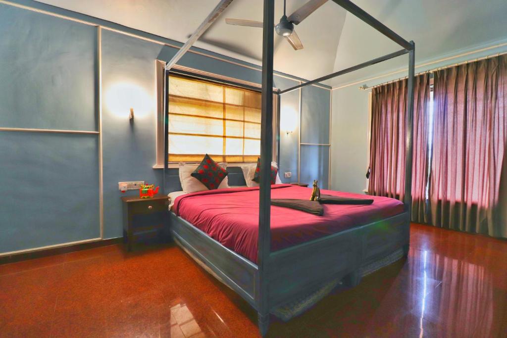 a bedroom with a canopy bed with a red bedspread at Velvet Rooms By 29bungalow in Lonavala