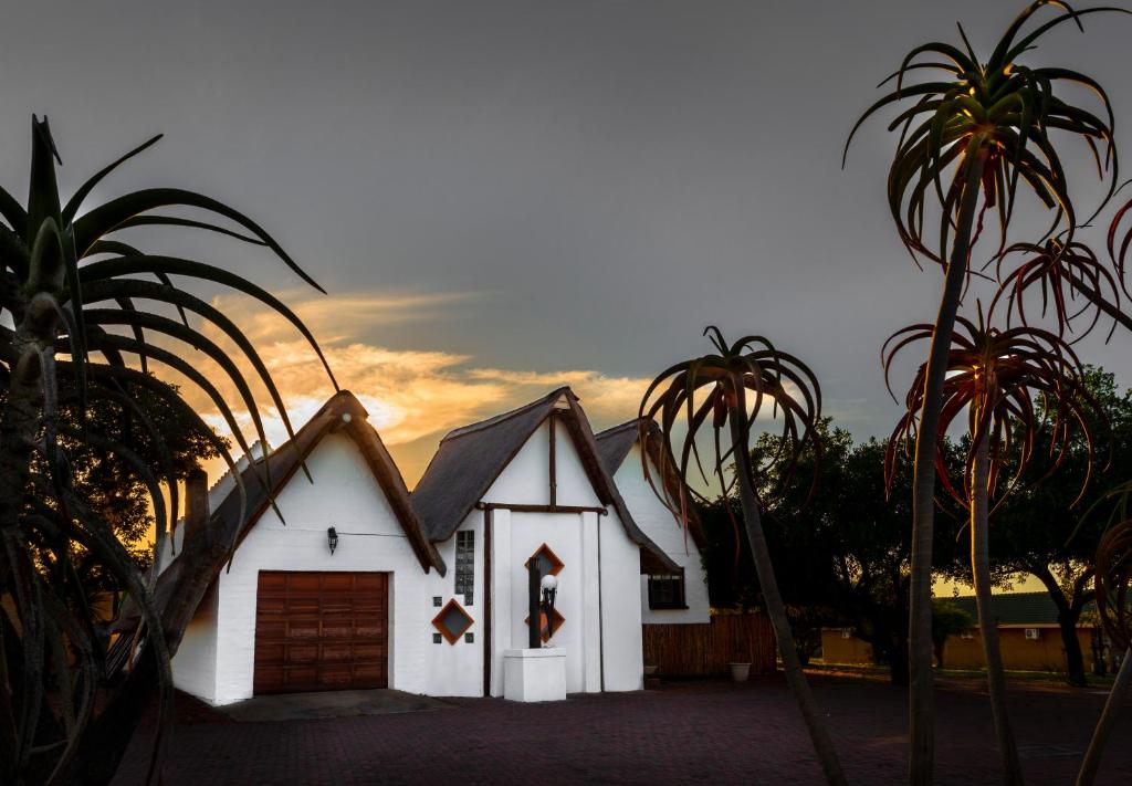 una pequeña casa blanca con garaje y palmeras en Bolivia Lodge, en Polokwane