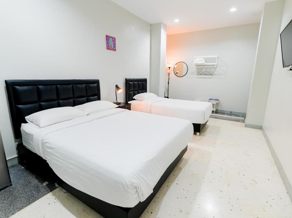 two beds in a hotel room with white sheets at Suksomboon Residence in Bangkok