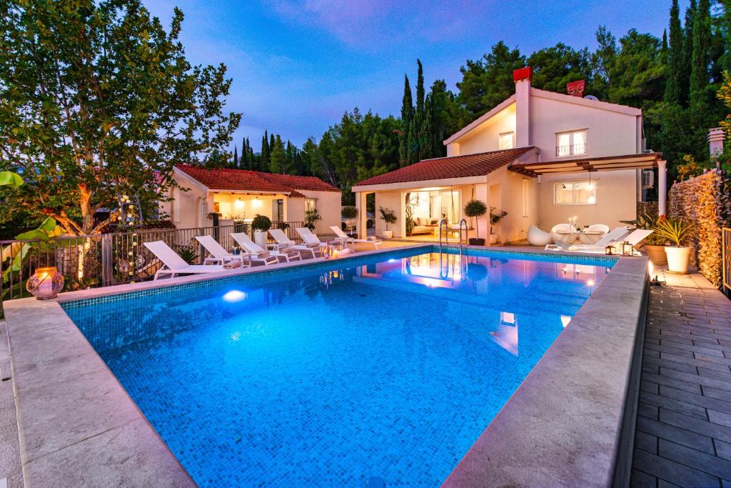 uma piscina com cadeiras e uma casa em Luxury Vila Divina-Exceptional privacy em Mlini