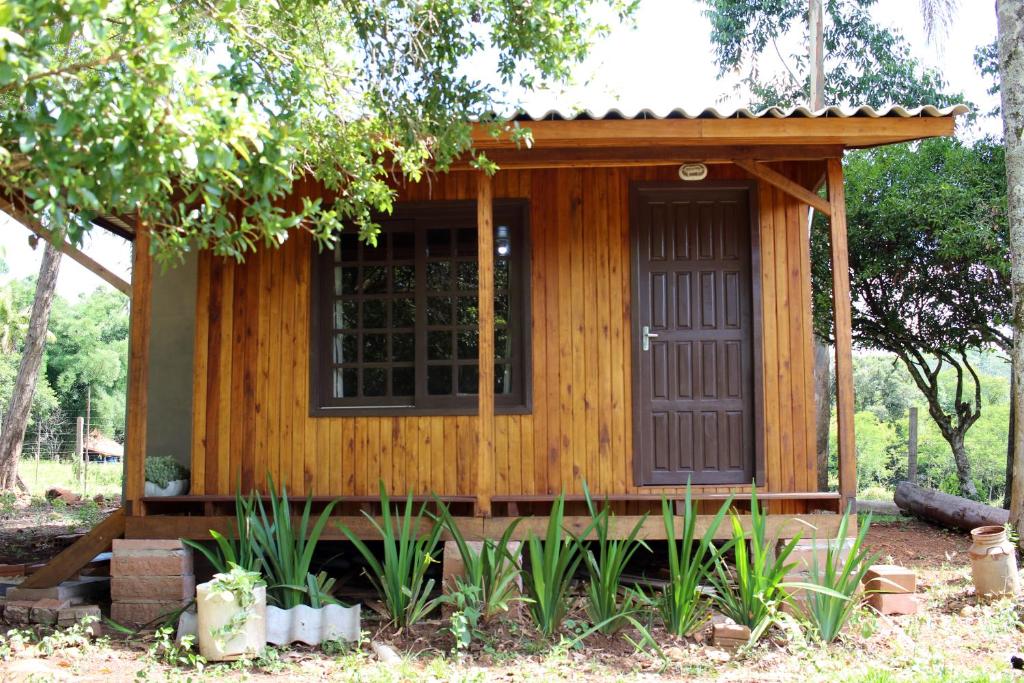 a small wooden cabin with a door in a garden at Cabana na Serra Gaúcha! in Picada Cafe