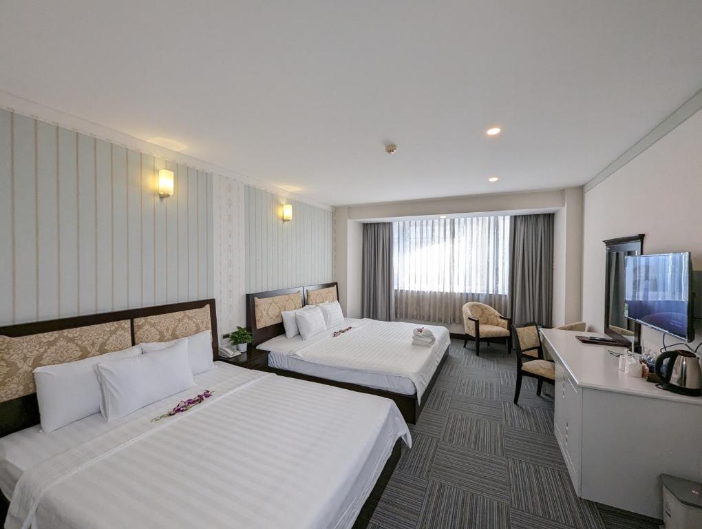 Habitación de hotel con 2 camas y TV de pantalla plana. en Đông Kinh Hotel en Ho Chi Minh