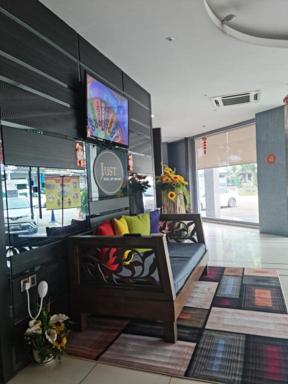a lobby with a bench and a tv in a store at Just Hotel BP in Batu Pahat