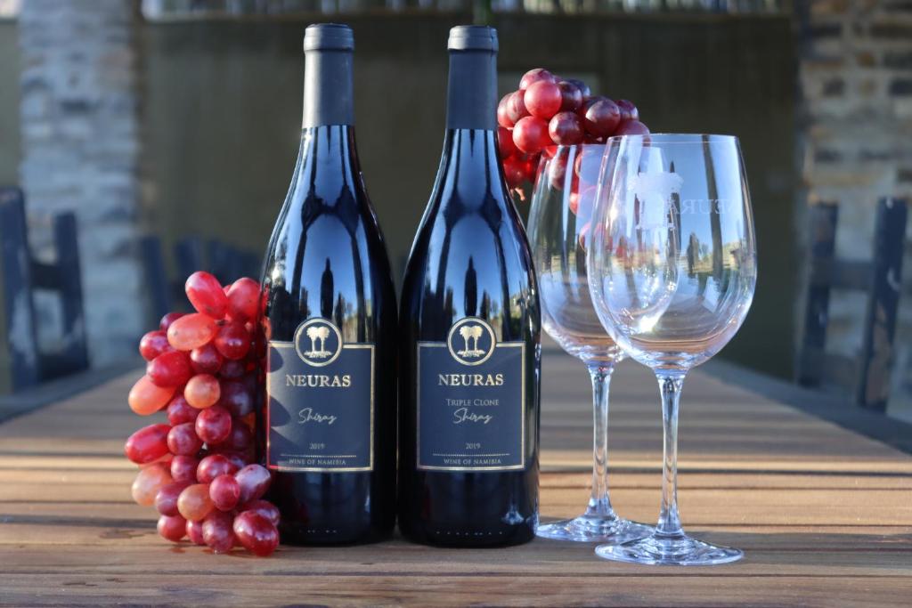 dwie butelki wina obok grona winogron w obiekcie Neuras Wine and Wildlife Estate w mieście Naukluft Mountains