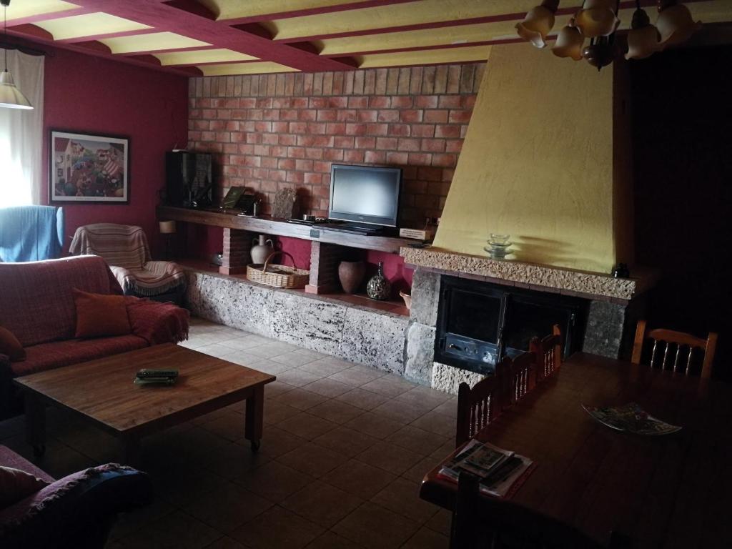 a living room with a fireplace with a television and a table at CASA RURAL RIO CABRIEL in Villamalea