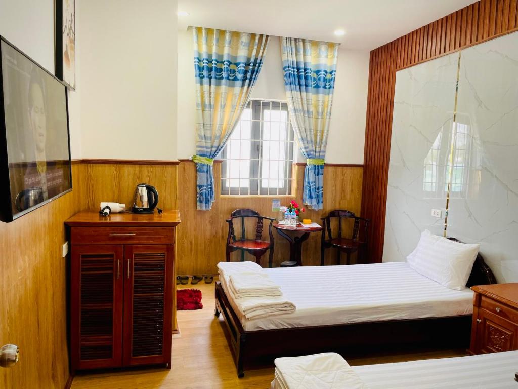 トゥイホアにあるNhu Y Hotelのベッド2台、テーブルと椅子が備わるホテルルームです。