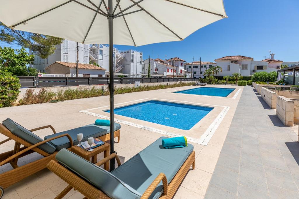 a pool with chairs and an umbrella and a swimming pool at Apartment La Nau - Fantastic Apartment with hot tub and pool, just steps away from beach in Port de Pollensa