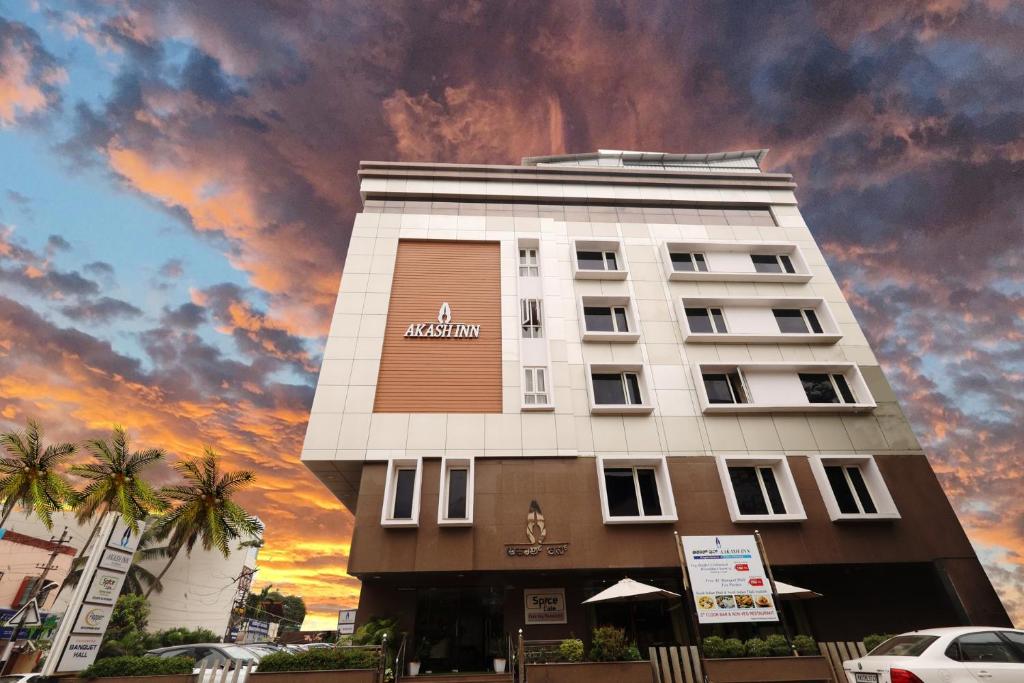 un edificio de hotel con un cielo nublado en el fondo en Akash Inn, en Shimoga