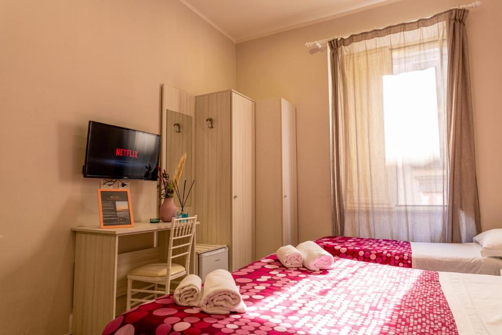 a bedroom with two beds and a tv and a window at B&B alla Ferrovia in Naples