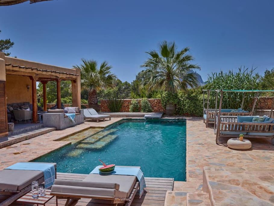 a swimming pool in a yard with chairs and a patio at Kasbah Darshan in Cala Vadella