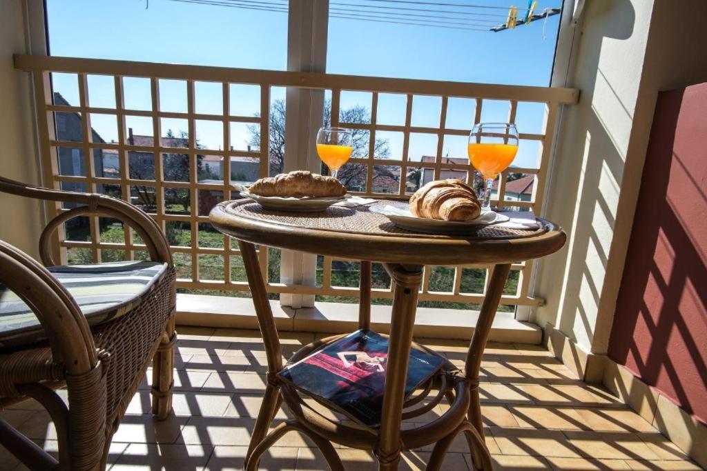 uma mesa na varanda com 2 copos de sumo de laranja em Noemi Apartment em Zadar