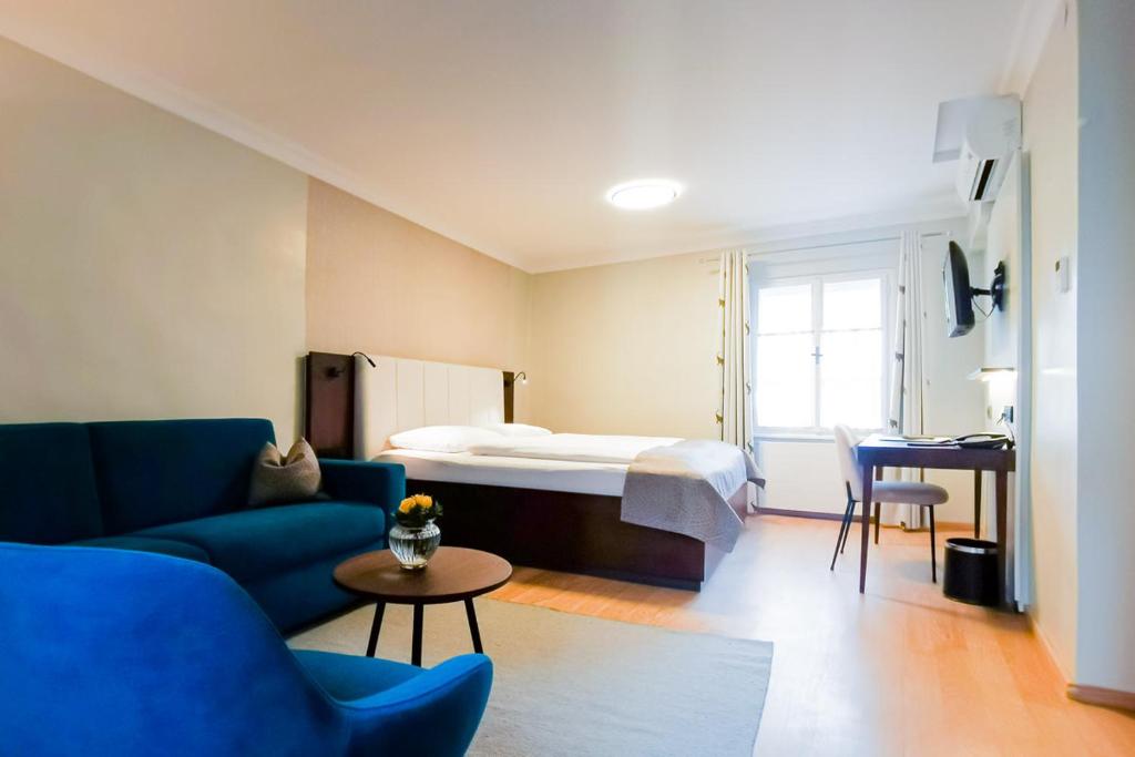a room with a bed and a couch and a table at Hotel Elefant in Salzburg