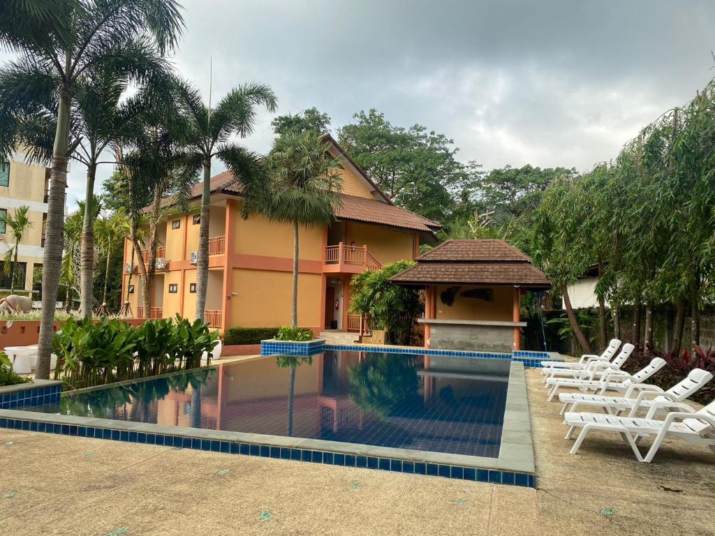 uma piscina em frente a um edifício com cadeiras brancas em Du-sila Hotel kohchang em Ko Chang