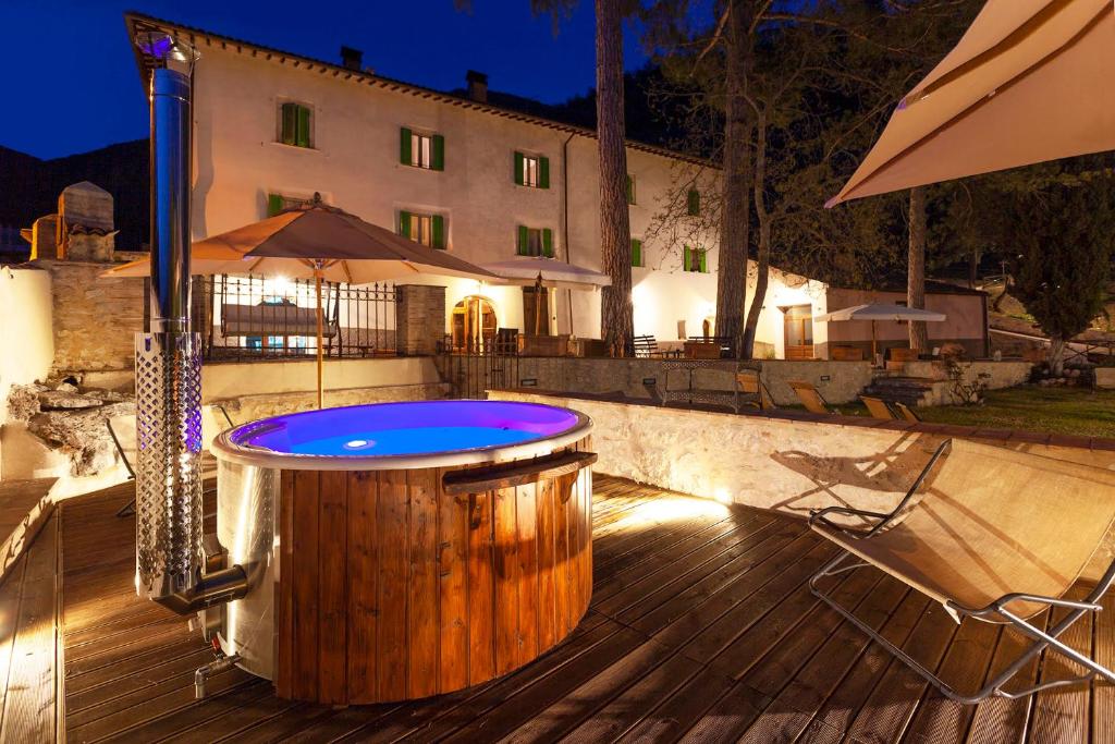 a hot tub on a wooden deck with a building at FonteAntica Agriturismo in Norcia