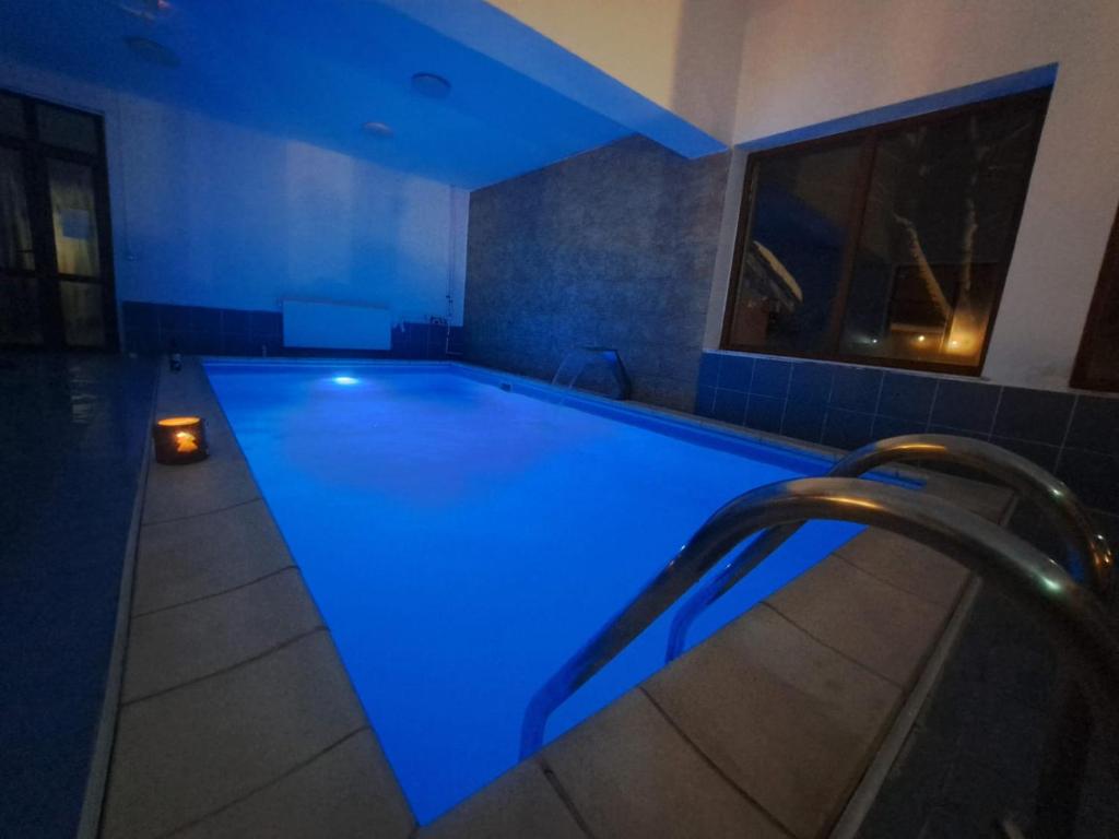 uma piscina com iluminação azul num edifício em Pensiunea Montan din Bran,sat Simon SPA indoor em Bran