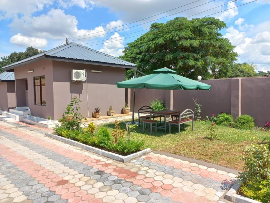 a house with a table and an umbrella in the yard at Kasuda - self contained room in Livingstone in Livingstone