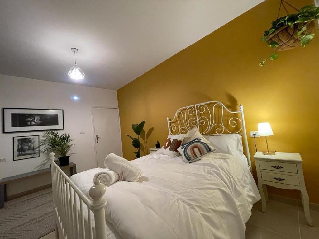 sypialnia z białym łóżkiem i żółtą ścianą w obiekcie Zaatar House w mieście Bethlehem