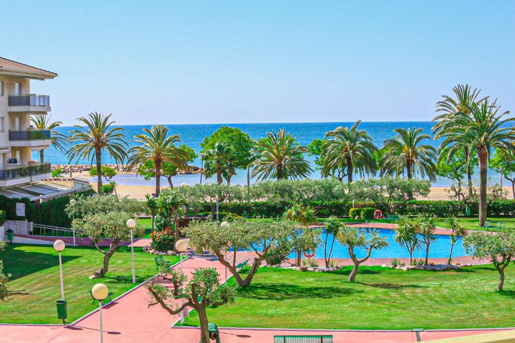 a resort with a pool and palm trees and the ocean at Golf D 201 ONLY FAMILIES in Cambrils