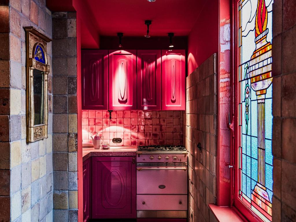 a red kitchen with pink cabinets and a stove at Private and chique Salon de Franz - with large terrace in Amsterdam